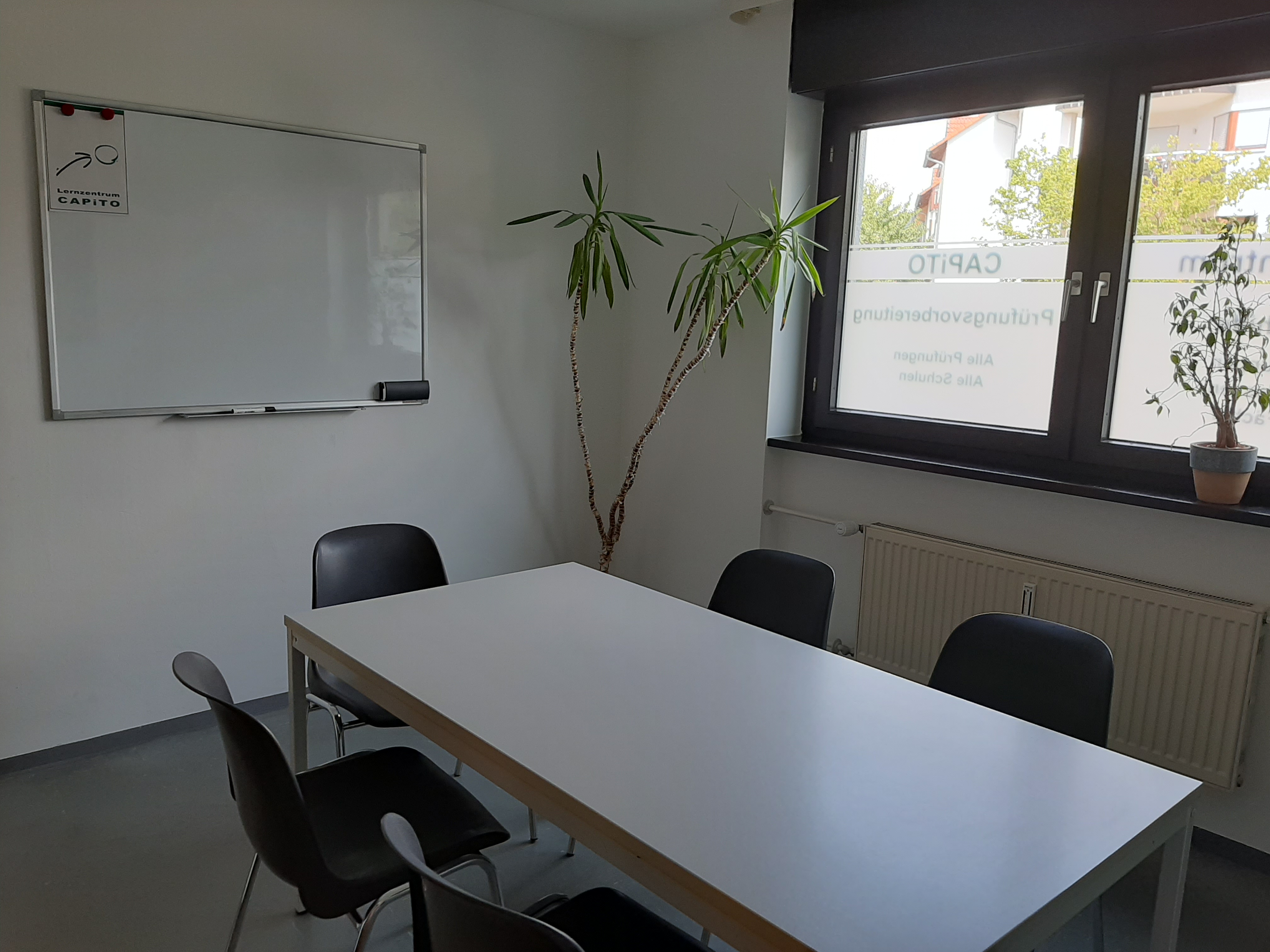 Schulungsraum mit Tisch und Stühlen sowie Whiteboard
