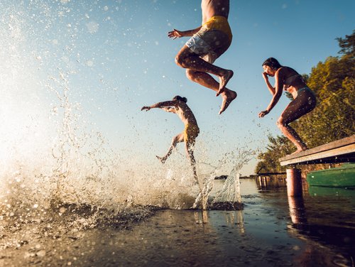 Kinder springen von einem Steg ins Wasser