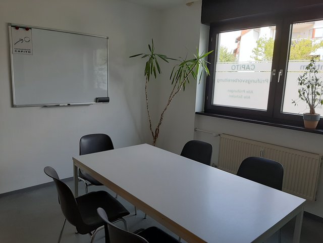 Schulungsraum mit Tisch und Stühlen sowie Whiteboard