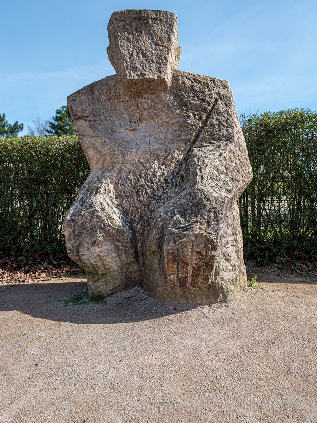 hockende Figur aus Stein in Übergröße